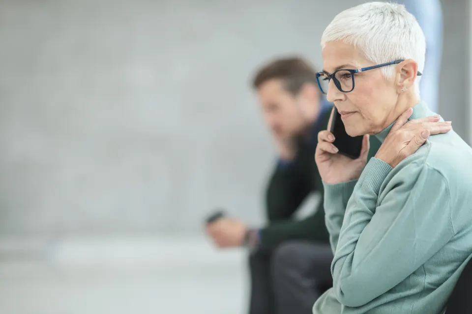 A woman with glasses listening carefully on a phone call