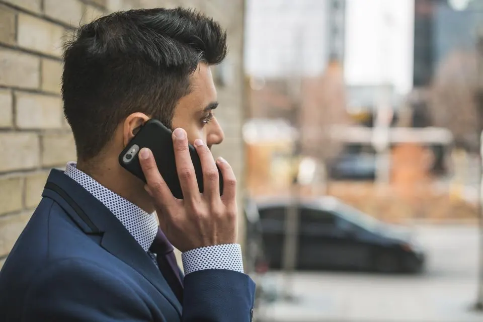 A man in a suit taking a phone call outside an office building